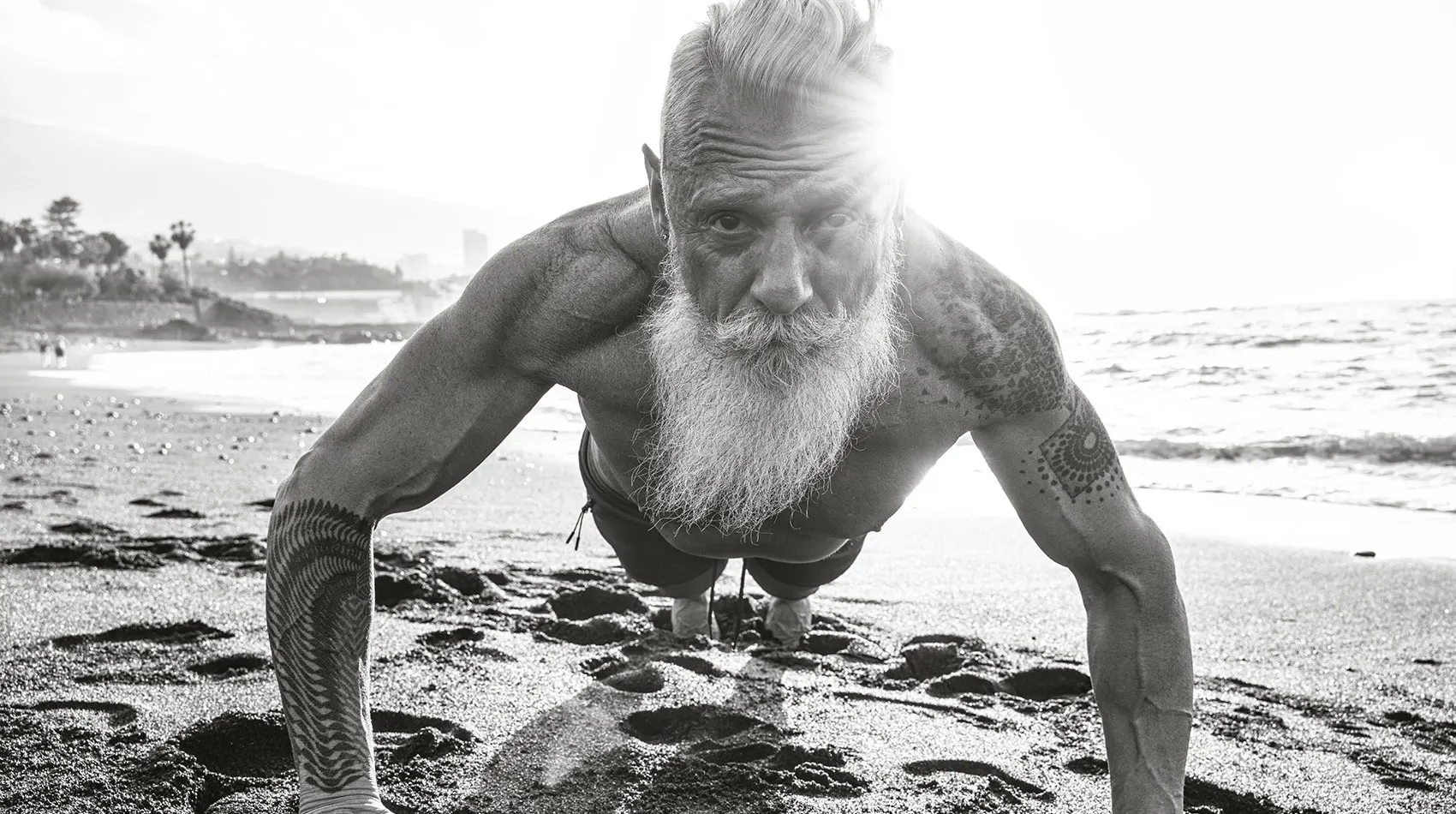 Fit retired man doing pushups on the beach